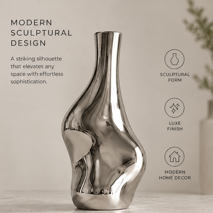 Mirror silver sculptural wave vase with white calla lilies displayed on a marble console table beside framed art